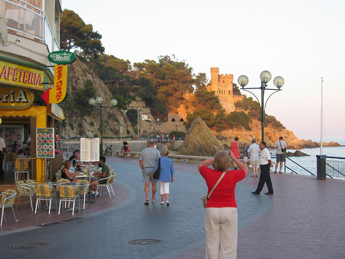 Una visitante toma una foto del Castillo d'en Plaja, en el lado norte de la Platja de Lloret, junto a la cala de Sa Caleta