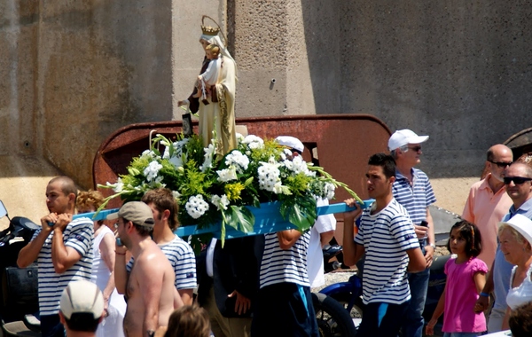 La imagen de la Virgen del Carmen es portada por los devotos del pueblo, acompañada de la banda de música, hacia el puerto, donde la espera la embarcación que la llevará mar adentro, a la Playa de Garbet, en el límite entre Llançà y Colera